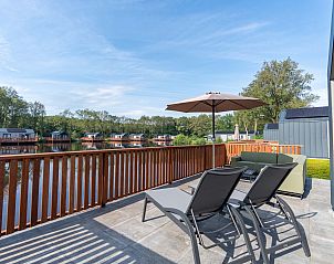 Terras met ligstoelen en parasol bij Vrijstaande woning in Sellingen, vakantiehuis aan het water in Groningen.
