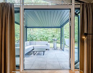 Terras met zithoek in vakantiehuis Sellingen, Groningen, omgeven door natuur.