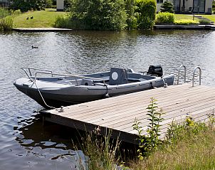 Priv aanlegsteiger met boot bij Vakantiehuis Lieskehuis Wellness de Luxe 10+2 in Vlagtwedde, ideaal voor watersportliefhebbers.