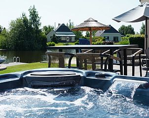 Bubbelbad met uitzicht op het water bij Vakantiehuis Lieskehuis Wellness de Luxe 10+2, Vlagtwedde, voor ultieme ontspanning.