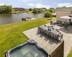 Terras met jacuzzi en uitzicht op water bij Vakantiehuis Lieskehuis Wellness de Luxe 10+2, Vlagtwedde, ideaal voor ontspanning.