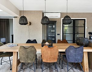 Eetkamer in Vakantiehuis Metbroekhuis Wellness de Luxe, Vlagtwedde, met kleurrijke stoelen en moderne lampen.