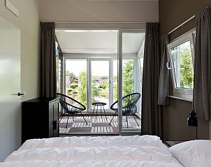 Slaapkamer met balkon in Vakantiehuis Metbroekhuis Wellness de Luxe, Vlagtwedde, met uitzicht op de natuur.