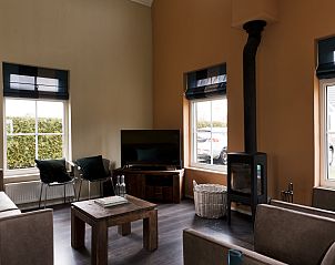 Gezellige woonkamer in Vakantiehuis Heerd Wellness de Luxe, Vlagtwedde, met open haard en comfortabele zitplaatsen.