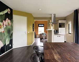 Eetruimte in Vakantiehuis Heerd Wellness de Luxe, Vlagtwedde, met kleurrijke muurdecoratie.