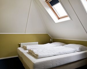 Zolder slaapkamer in Vakantiehuis Heerd Wellness de Luxe, Vlagtwedde, met schuin dak en dakraam.