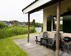 Terras met barbecue bij Vakantiehuis Heerd Wellness de Luxe, Vlagtwedde, met uitzicht op het water.