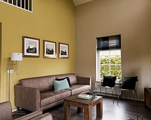 Gezellige zithoek in Vakantiehuis Heerd Wellness de Luxe, Vlagtwedde, met kunst aan de muur.