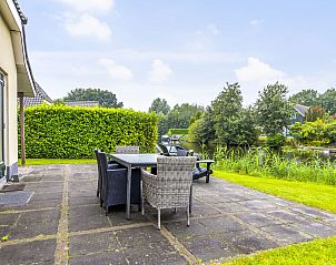 Ruim terras met eettafel bij Vakantiehuis Heerd Wellness de Luxe, Vlagtwedde, met uitzicht op het water.