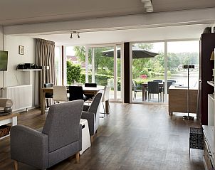 Lichte woonkamer van Vakantiehuis Vrieschehuis Comfort Royaal in Vlagtwedde met uitzicht op de tuin, perfect voor een ontspannen verblijf.