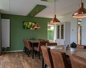 Stijlvolle eetkamer van Wellness 14 bungalow in Vlagtwedde, Zuidoost Groningen, met houten vloer en moderne koperen lampen.