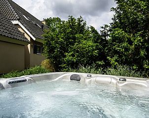 Bubbelende spa bij Vakantiehuis Vosseberghuis Prestige & Outdoor Spa in Vlagtwedde, omgeven door groen.