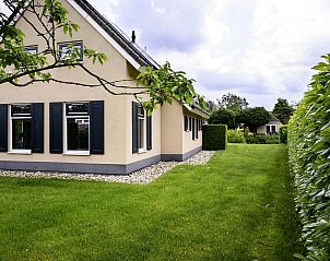 Zijaanzicht van Vakantiehuis Vosseberghuis Prestige & Outdoor Spa in Vlagtwedde, met groene tuin.