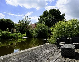 Terras aan het water bij Vakantiehuis Vosseberghuis Prestige & Outdoor Spa, Vlagtwedde, met comfortabele zitplekken.