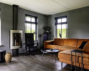 Gezellige zithoek in Vakantiehuis Vosseberghuis Prestige & Outdoor Spa, Vlagtwedde, met moderne open haard.