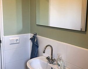 Frisse badkamer in Huisje in Slochteren, vakantiehuis in Groningen met spiegel en wastafel.