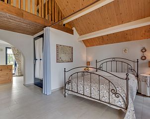 Sfeervolle slaapkamer met houten balken in Vakantiehuis Westerwolde, Onstwedde, voor een rustgevende nacht in Groningen.