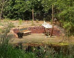 Zithoek met hangmat bij de vijver van Vakantiehuis in Veelerveen, biedt een ontspannend verblijf in Zuidoost Groningen.