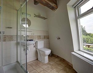 Gezellige woonkamer van GR029 in Tripscompagnie, Groningen met een sfeervolle spiraaltrap en houten balkenplafond.