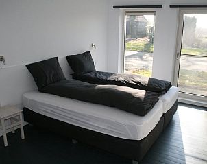 Lichte slaapkamer in Huisje in Mussel, vakantiehuis in Zuidoost Groningen met groot bed en tuinzicht.