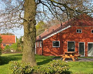 Zijaanzicht van Huisje in Mussel, vakantiehuis in Groningen met picknicktafel en groene omgeving.