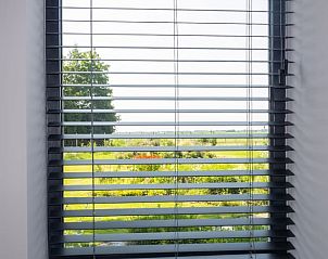 Uitzicht vanuit het raam van Vakantiehuisje in Kiel-Windeweer, Zuidoost Groningen, met groene tuinen en blauwe luchten.