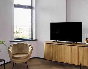 Lichte woonkamer in Vakantiehuisje in Kiel-Windeweer, Zuidoost Groningen, met een comfortabele stoel en moderne televisie.