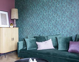 Stijlvolle zithoek in Vakantiehuisje in Kiel-Windeweer, Zuidoost Groningen, met een groene bank en kleurrijke decoratie.