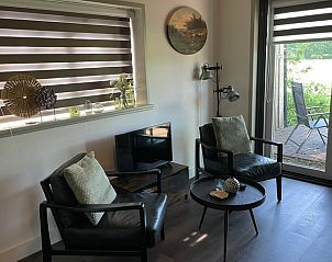 Zithoek met uitzicht op terras in Vakantiehuisje in Noordwijk, Groningen.