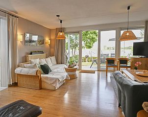 Gezellige woonkamer in Aan de Oever vakantiehuis, Stevensweert met uitzicht op tuin en water.