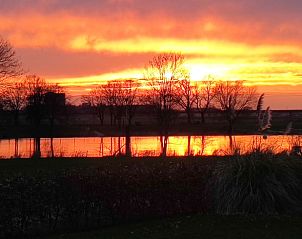 Prachtige zonsondergang bij Huisje in Well, vakantiehuis in Noord Limburg met uitzicht op serene natuur en waterlandschap.