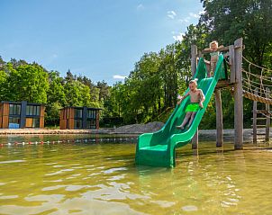 Kinderen spelen op glijbaan bij het meer van Vakantiehuis Cube Magnifique 10 in Belfeld, Noord Limburg.