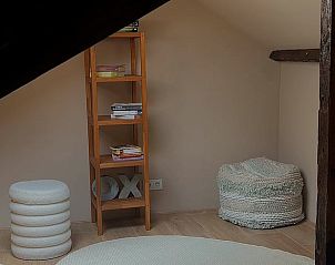 Gezellige leeshoek op zolder van Vakantiehuisje in America, Noord Limburg, met boekenplank en poef.