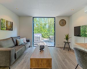 Bright living room of Bos Cabin with Jacuzzi for 2 people in Maasbree, North Limburg, overlooking terrace and nature.
