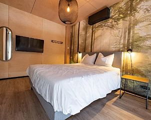 Luxurises Schlafzimmer in Bos Villa DeLuxe XL in Maasbree, Nord-Limburg, mit bequemem Bett und stimmungsvoller Waldwanddekoration.