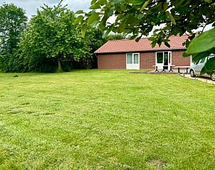 Uitgestrekt grasveld bij Vakantiehuis in Beesel, Noord Limburg, met bomen en auto.