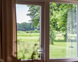 Uitzicht op groene tuin vanuit Vakantiehuis in Beesel, Noord Limburg, door groot raam.