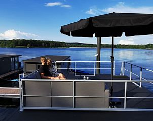 Ontspan op het terras van Vakantiehuisje in Middelaar, Noord Limburg, met uitzicht op het serene water en de groene omgeving.