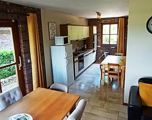 Cozy kitchen and dining area in Huisje in Mechelen, a vacation home in South Limburg, with wooden furniture and views of the green surroundings.
