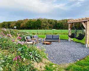 Zithoek in de tuin van Vakantiehuisje in Wijlre, Zuid-Limburg, omgeven door bloemen en groen.