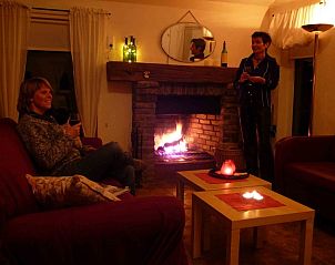 Gezellige woonkamer met open haard in Vakantiewoning 'in de Boomgaard' in Oud Roosteren, ideaal voor een ontspannen avond in Limburg.