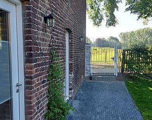 Buitenkant van vakantiehuis Wittem, Zuid Limburg, met toegangspoort en groene omgeving.