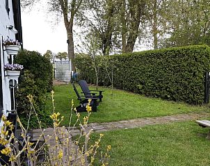 Rustige tuin bij Vakantiehuisje in Aarle-Rixtel, De Peel, met zitplaatsen en groene heg.