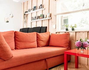 Comfortabele oranje sofa in de woonkamer van Huisje in Helmond, vakantiehuis in De Peel, Noord Brabant.
