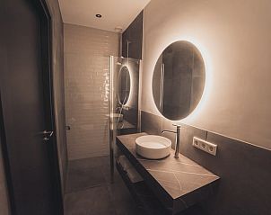 Stijlvolle badkamer met verlichte spiegel in Huisje in Milheeze, vakantiehuis in De Peel, Noord Brabant.