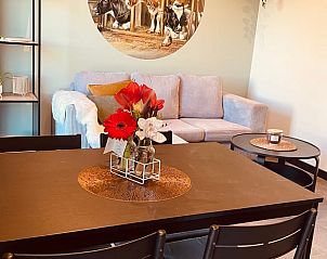 Eethoek in Vakantiehuisje in Liessel, De Peel, Noord Brabant met bloemen op tafel en een schilderij van koeien aan de muur.