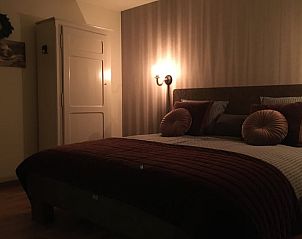 Sfeervolle slaapkamer in Vakantiehuisje in De Rips, De Peel, Noord Brabant met warm verlichte muren en comfortabel bed.
