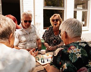 Gezellige groep mensen geniet van een bordspel op het terras van Vakantiehuisje in Bergeijk, Kempen.