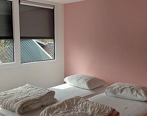 Slaapkamer met roze muur in Huisje in Oirschot, vakantiewoning in Noord Brabant.