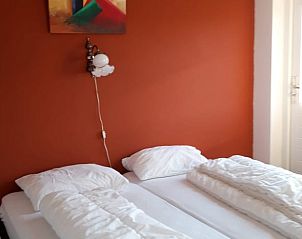 Slaapkamer met oranje muur in Huisje in Oirschot, vakantiewoning in Noord Brabant.
